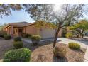 Single-story house with a tan exterior, two-car garage, and well-manicured landscaping at 40901 N Courage Trl, Anthem, AZ 85086