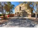 Two-story house with tan exterior, attached garage, and driveway, surrounded by trees at 5496 S 237Th Ln, Buckeye, AZ 85326