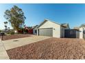 Single-story home with gray garage door and a gravel driveway at 7602 W Minnezona Ave, Phoenix, AZ 85033