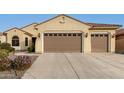 Tan two-story house with a three-car garage and landscaped front yard at 20359 N 262Nd Dr, Buckeye, AZ 85396