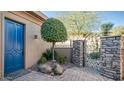 A blue door and lush greenery create a welcoming entry courtyard at 211 E Desert Wind Dr, Phoenix, AZ 85048