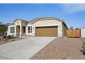 Front view of a beige house with a brown garage door and wood fence at 44478 W Palo Abeto Dr, Maricopa, AZ 85138