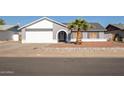 Single-story house with a gray exterior, white garage door, and a palm tree in the front yard at 7210 W Pasadena Ave, Glendale, AZ 85303