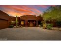 Exterior of a Southwestern style home with a brick driveway and desert landscaping at sunset at 25555 N Wrangler Rd, Scottsdale, AZ 85255