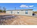 Rear view of a manufactured home, showcasing a side door and landscaping at 10991 W Hilltop Dr, Casa Grande, AZ 85193