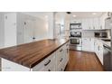 Kitchen with butcher block island, white cabinets, stainless steel appliances, and wood flooring at 3606 E Osborn Rd, Phoenix, AZ 85018