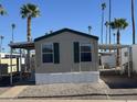 Tan mobile home with carport and a white base; surrounded by palm trees at 2701 E Allred Ave # 110, Mesa, AZ 85204