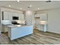 Spacious kitchen with island, white cabinets, and wood-look flooring at 15371 W Desert Hollow Dr, Surprise, AZ 85387