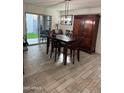 Dining room with wood-look floors, rustic wood table and decor with sliding glass patio doors at 16405 W Latham St, Goodyear, AZ 85338