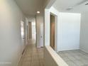 Clean hallway with tile floors and neutral-colored walls at 42025 W Manderas Ln, Maricopa, AZ 85138