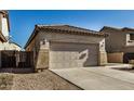 Tan house with tile roof and two-car garage.Landscaped yard at 42788 W Martie Lynn Rd, Maricopa, AZ 85138