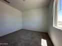 A carpeted bedroom with a large window, perfect for enjoying the natural light and neighborhood views at 47250 W Mellen Ln, Maricopa, AZ 85139