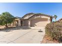 Tan house with a two-car garage and desert landscaping at 5426 N Rattler Way, Litchfield Park, AZ 85340