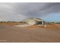 Tan house with covered porch, attached garage, and landscaped yard at 10428 S 294Th Ave, Palo Verde, AZ 85343