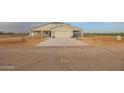 Tan house with covered porch, attached garage, and landscaped yard at 10428 S 294Th Ave, Palo Verde, AZ 85343