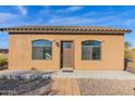 Front view of a small house with a brown door and arched windows at 12692 W Toltec Cir, Casa Grande, AZ 85194