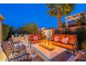 Inviting backyard with comfortable seating arranged around a tile-lined fire pit, palm trees, and BBQ grill at 1397 E Verde Blvd, Queen Creek, AZ 85140