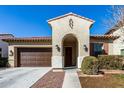 Inviting single-story home with an arched entryway, a brown garage door, and manicured front yard landscaping at 20496 W Valley View Dr, Buckeye, AZ 85396