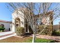 Charming single-story home featuring an arched entryway, and a meticulously maintained front yard with a decorative tree at 20496 W Valley View Dr, Buckeye, AZ 85396