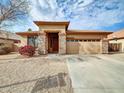 Tan stucco house with a tile roof, stone accents, and a two-car garage at 2706 N 115Th Dr, Avondale, AZ 85392