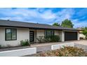 Home exterior featuring desert landscaping, a black garage door, modern front door and a white stucco facade at 4916 E Kathleen Rd, Scottsdale, AZ 85254