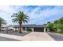 Charming single-story home featuring desert landscaping and a black garage door with a clear blue sky overhead at 4916 E Kathleen Rd, Scottsdale, AZ 85254