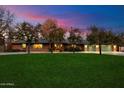 Charming red brick home with a lush green lawn and flowering trees set against a dramatic dusk sky at 8031 N 14Th Ave, Phoenix, AZ 85021