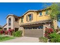 The side of a two-story home featuring a stone and stucco exterior with a two car garage at 4813 S Quantum Way, Mesa, AZ 85212