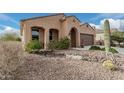 House exterior showcasing a tan stucco finish, desert landscaping, and a two-car garage at 8047 W Cinder Brook Way, Florence, AZ 85132