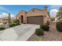 Front view of a tan house with a two-car garage and drought-tolerant landscaping at 8047 W Cinder Brook Way, Florence, AZ 85132