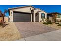 Modern one-story house with dark brown garage door and brick driveway at 17244 W Lynx Rd, Goodyear, AZ 85338