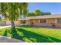 Brick ranch house with a large weeping willow tree and well-manicured lawn at 18202 N 99Th Dr, Sun City, AZ 85373