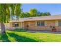Brick ranch house with a large weeping willow tree and well-manicured lawn at 18202 N 99Th Dr, Sun City, AZ 85373