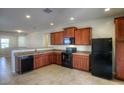 Kitchen features dark wood cabinets, granite countertops, and black appliances at 22424 W La Pasada Blvd, Buckeye, AZ 85326