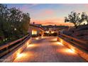 Beautiful stone home featuring a paver driveway, wooden fence, and professional landscaping at dusk at 16117 E Shooting Star Trl, Fountain Hills, AZ 85268