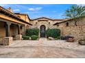 Elegant stone home showcasing a welcoming courtyard with lush greenery and well-maintained landscaping at 16117 E Shooting Star Trl, Fountain Hills, AZ 85268