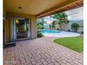 Inviting backyard featuring a refreshing pool, neat lawn, and brick-paved patio for outdoor relaxation and entertainment at 5345 E Evans Dr, Scottsdale, AZ 85254