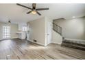 Open living area with laminate floors, ceiling fan, and stairs leading upstairs at 4565 N 26Th Dr, Phoenix, AZ 85017