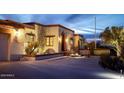 Evening view of a Spanish-style home with exterior lighting and landscaping at 7957 E Cave Creek Rd, Carefree, AZ 85377