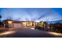 Evening view of a Spanish-style home with landscaping and driveway lighting at 7957 E Cave Creek Rd, Carefree, AZ 85377