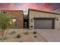 Modern home exterior with stone accents and landscaped front yard at sunset at 12411 E Troon Vista Dr, Scottsdale, AZ 85255