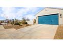 Two-car garage with teal doors and ample driveway space at 40634 W Hillman Dr, Maricopa, AZ 85138