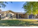 Tan house with dark garage door, covered patio, and landscaped yard at 8707 N 3Rd Ave, Phoenix, AZ 85021