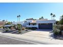 White stucco house with a gray garage door and nicely landscaped front yard at 9789 E Cinnabar Ave, Scottsdale, AZ 85258