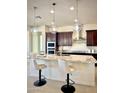 Bright kitchen featuring an island with pendant lighting, stainless steel appliances, and dark wood cabinetry at 22665 E Stacey Rd, Queen Creek, AZ 85142