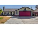 Single story home with a red garage door, landscaping, and basketball hoop at 7945 W Wethersfield Rd, Peoria, AZ 85381