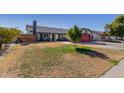 House with a large grassy yard, a red garage door, and a wooden fence at 7945 W Wethersfield Rd, Peoria, AZ 85381