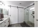 Updated bathroom with a barn door, chevron tile shower, and modern vanity at 9621 N 94Th Dr, Peoria, AZ 85345