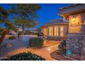 Inviting entryway with stonework, a walkway, and warm lighting at dusk at 15583 W Big Sky Dr, Surprise, AZ 85374