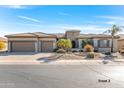 House exterior with a three-car garage and desert landscaping at 20621 N Canyon Whisper Dr, Surprise, AZ 85387